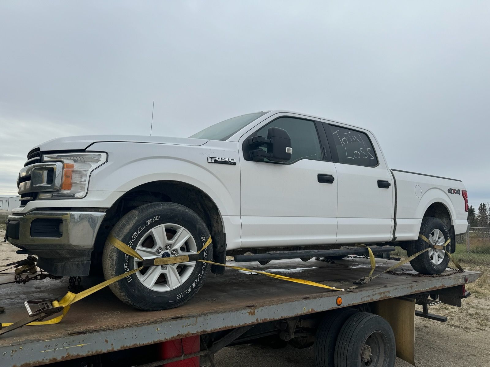 A white truck is being towed on our flatbed tow truck.