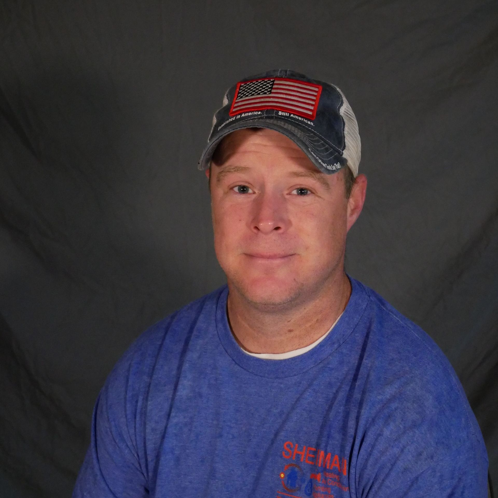 A man wearing a blue shirt and a hat with an american flag on it