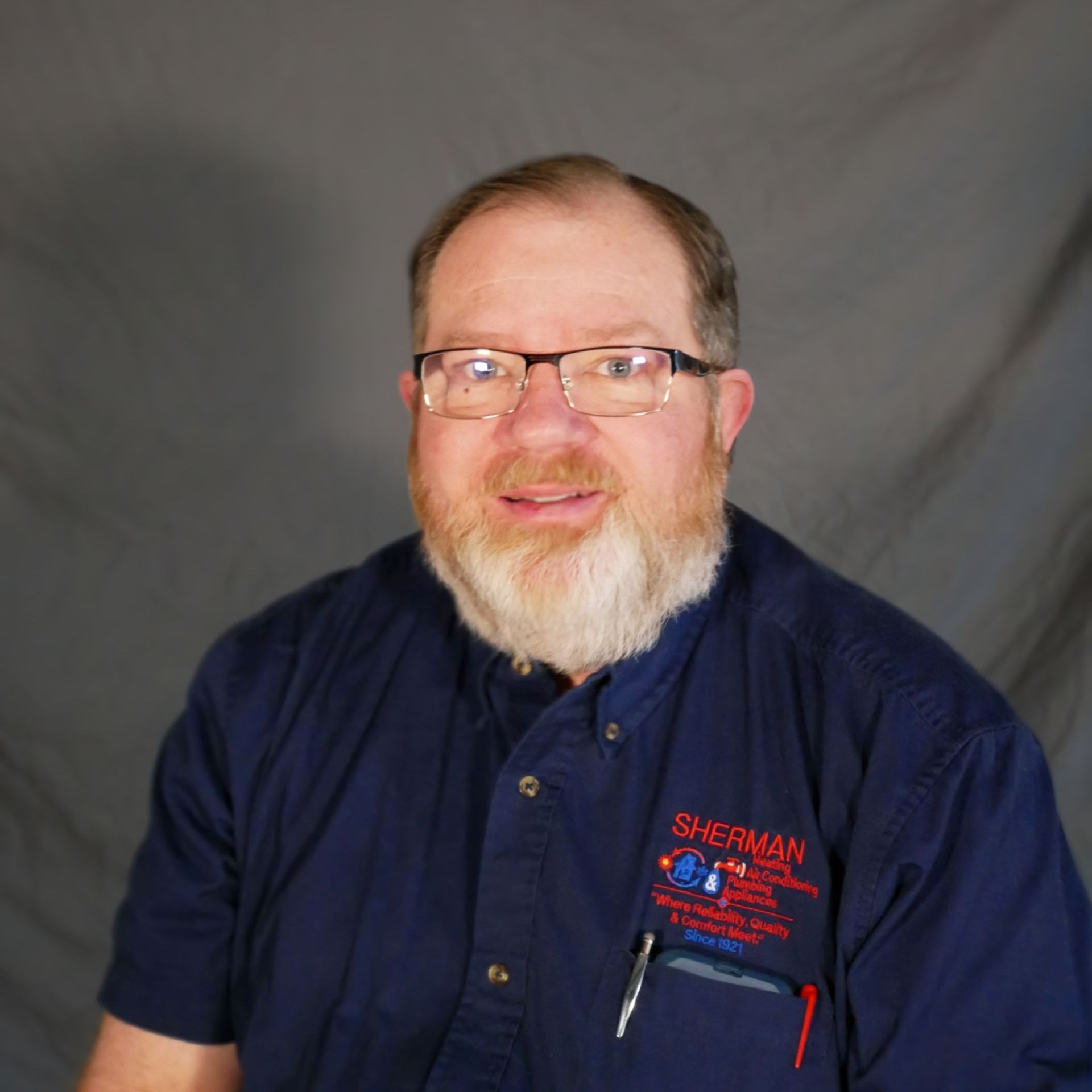 A man wearing glasses and a blue shirt that says sherman