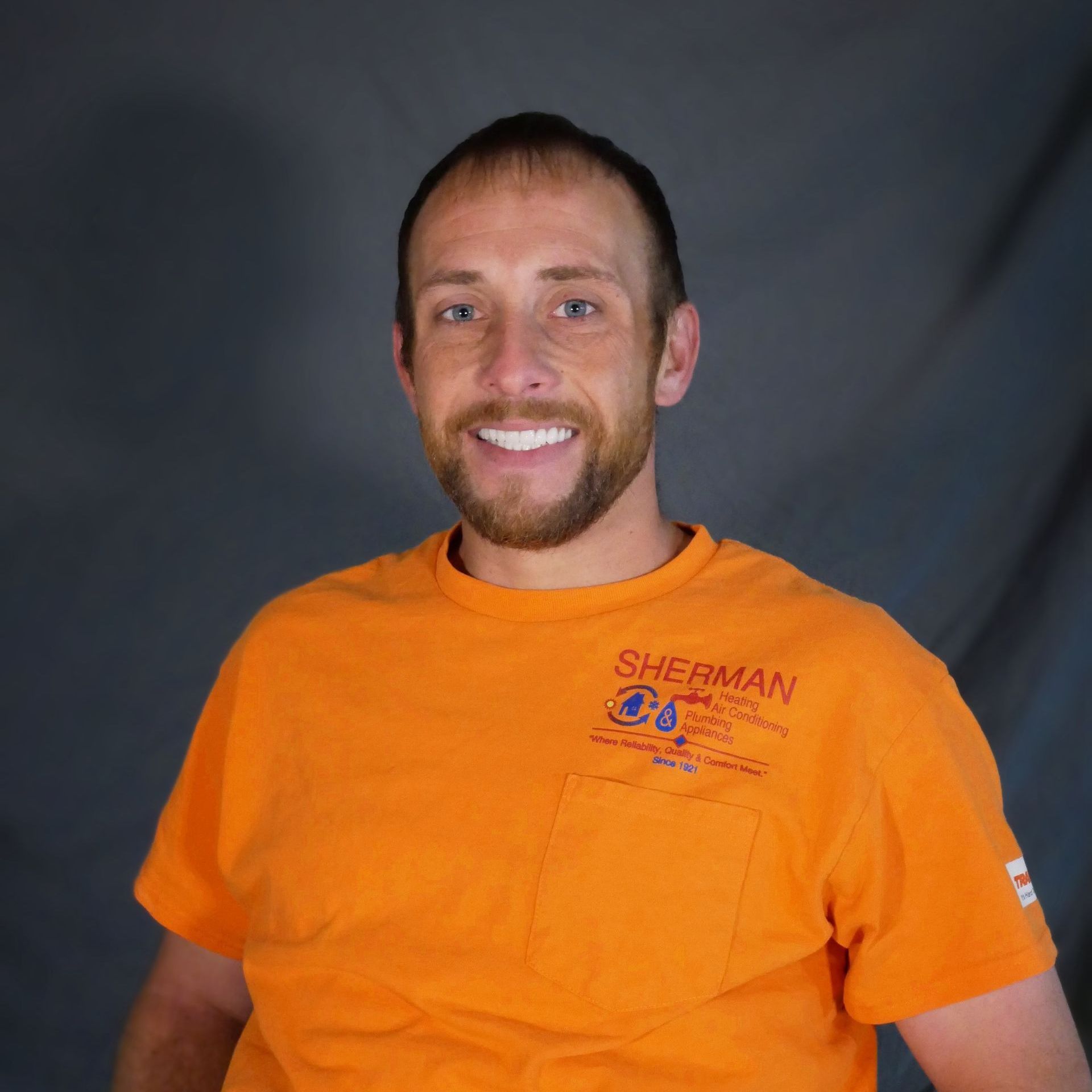 A man wearing an orange shirt with the word sherman on it