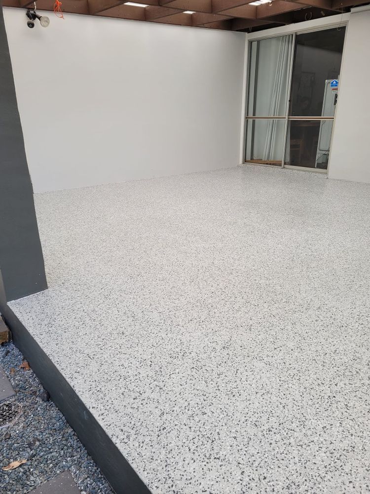 A Patio With a White Concrete Floor and a Sliding Glass Door — Mid North Coast Spray Pave in Port Macquarie, NSW