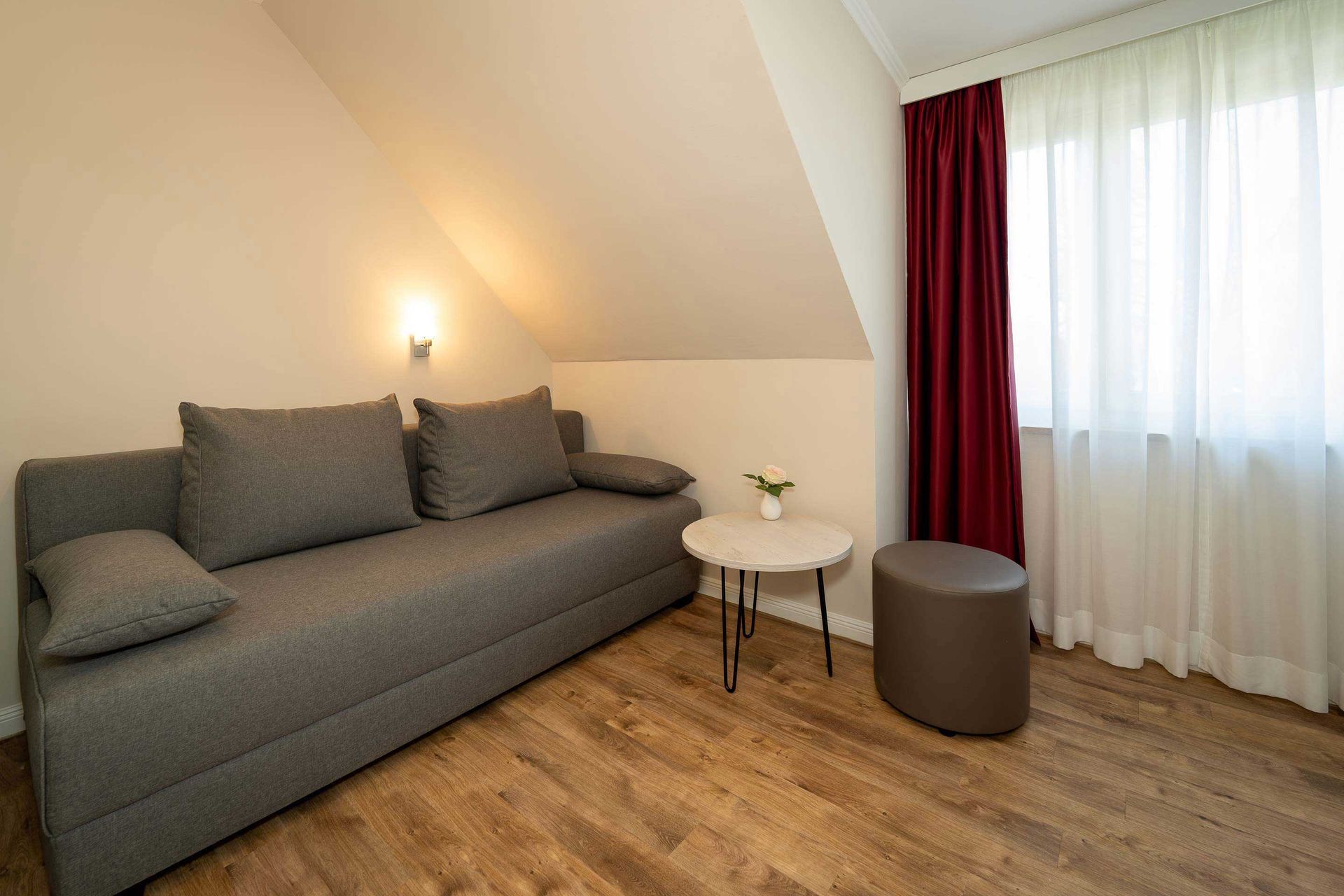 Wohnzimmer mit moderner Boxspring-Couch und hochwertiger Schlaffunktion im kleinen Apartment des Boutique Hotel Rosengarten.