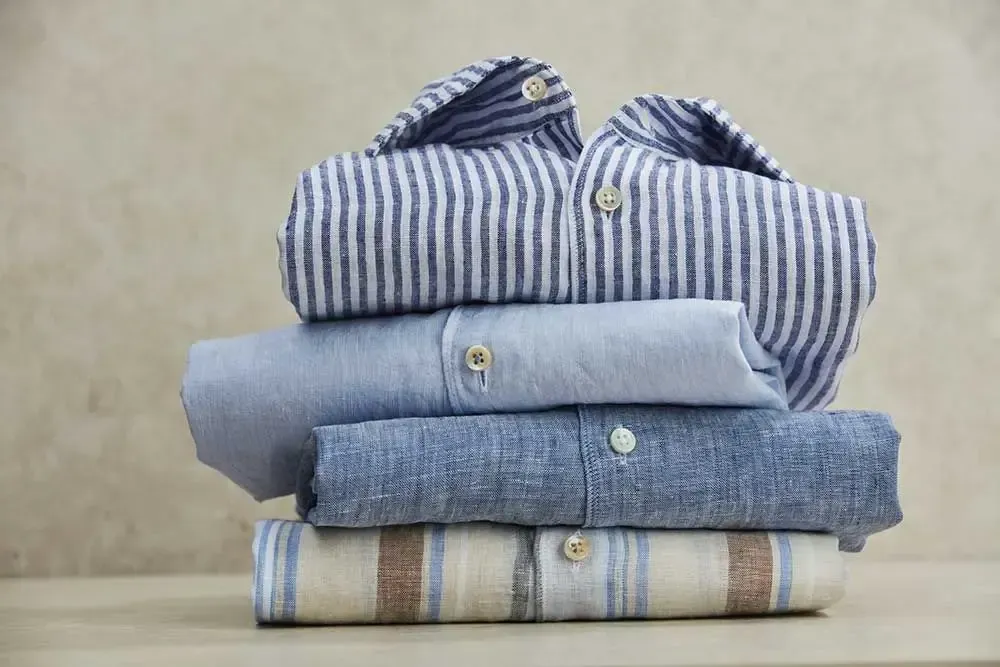 En stak foldede skjorter, der ligger oven på hinanden på et bord.