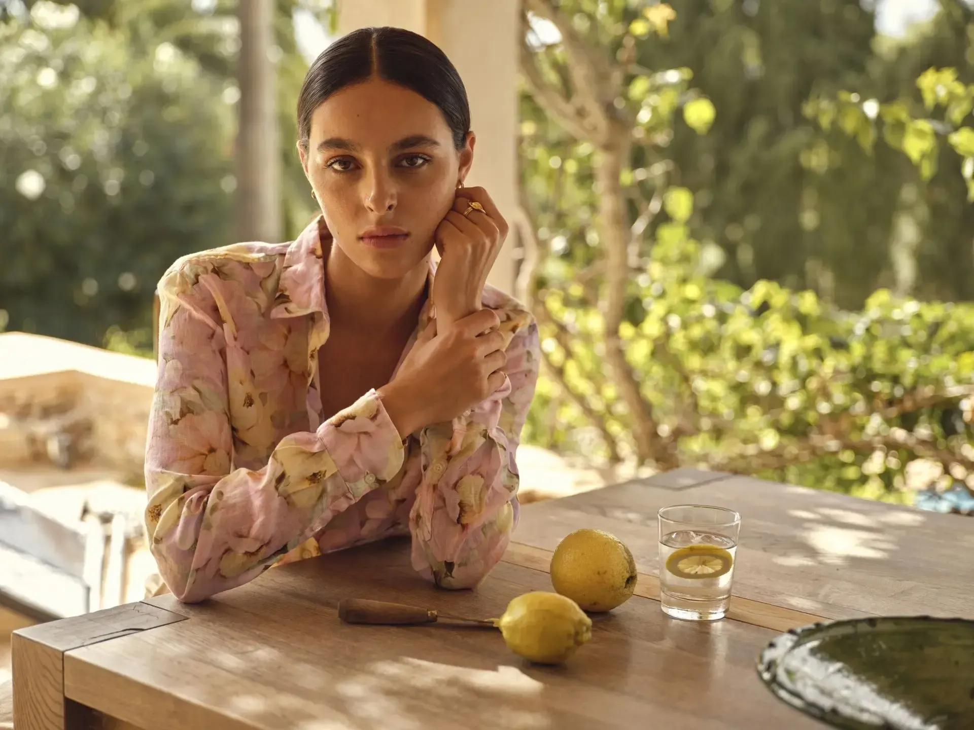 En kvinde sidder ved et bord med citroner og et glas vand.