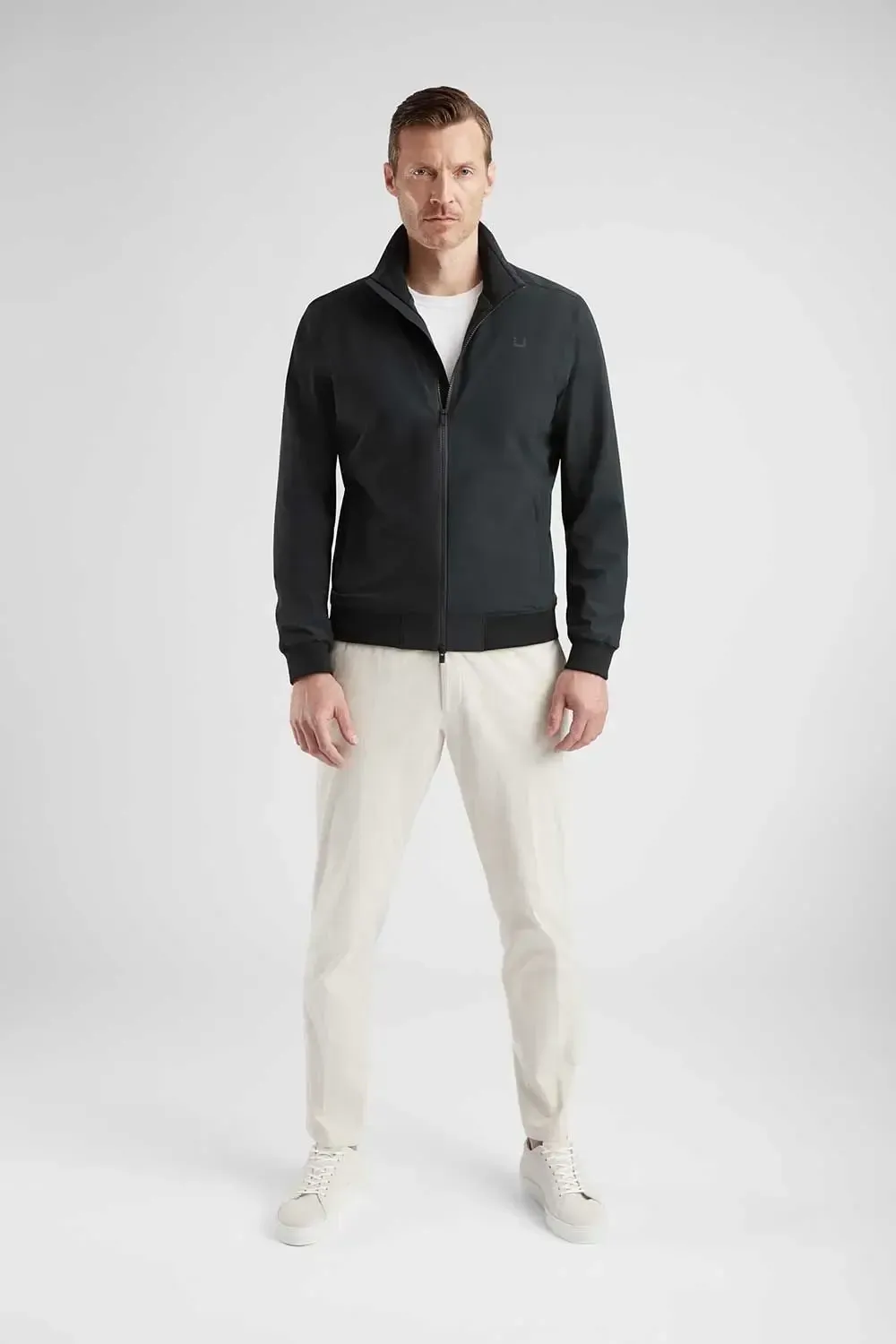 En mand har en sort jakke og hvide bukser på.