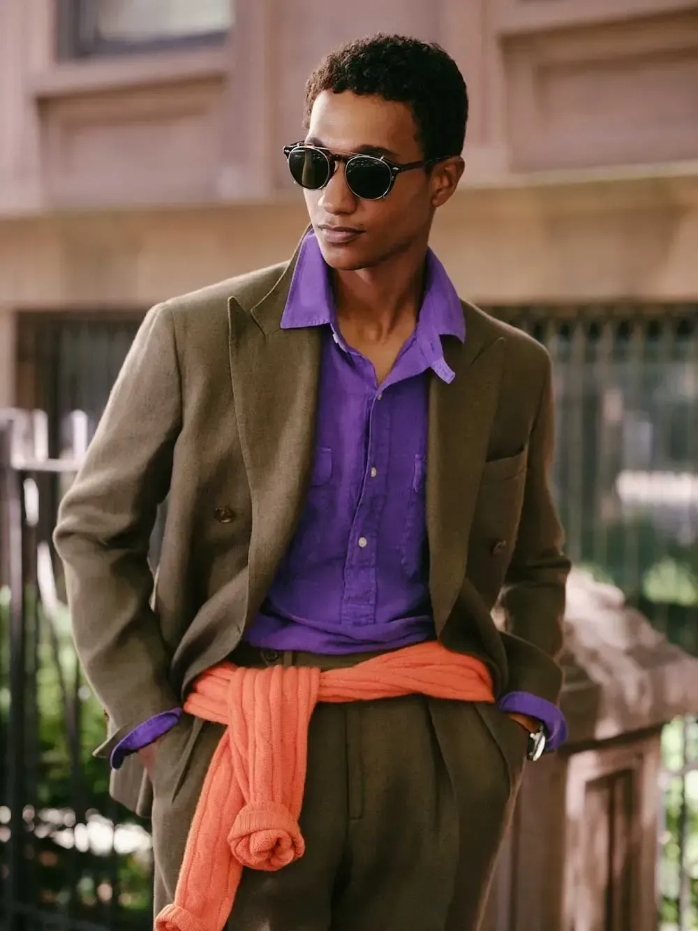 En mand iført jakkesæt og solbriller står foran en bygning.