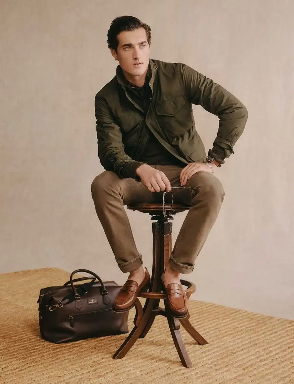 En mand sidder på en skammel ved siden af en taske.