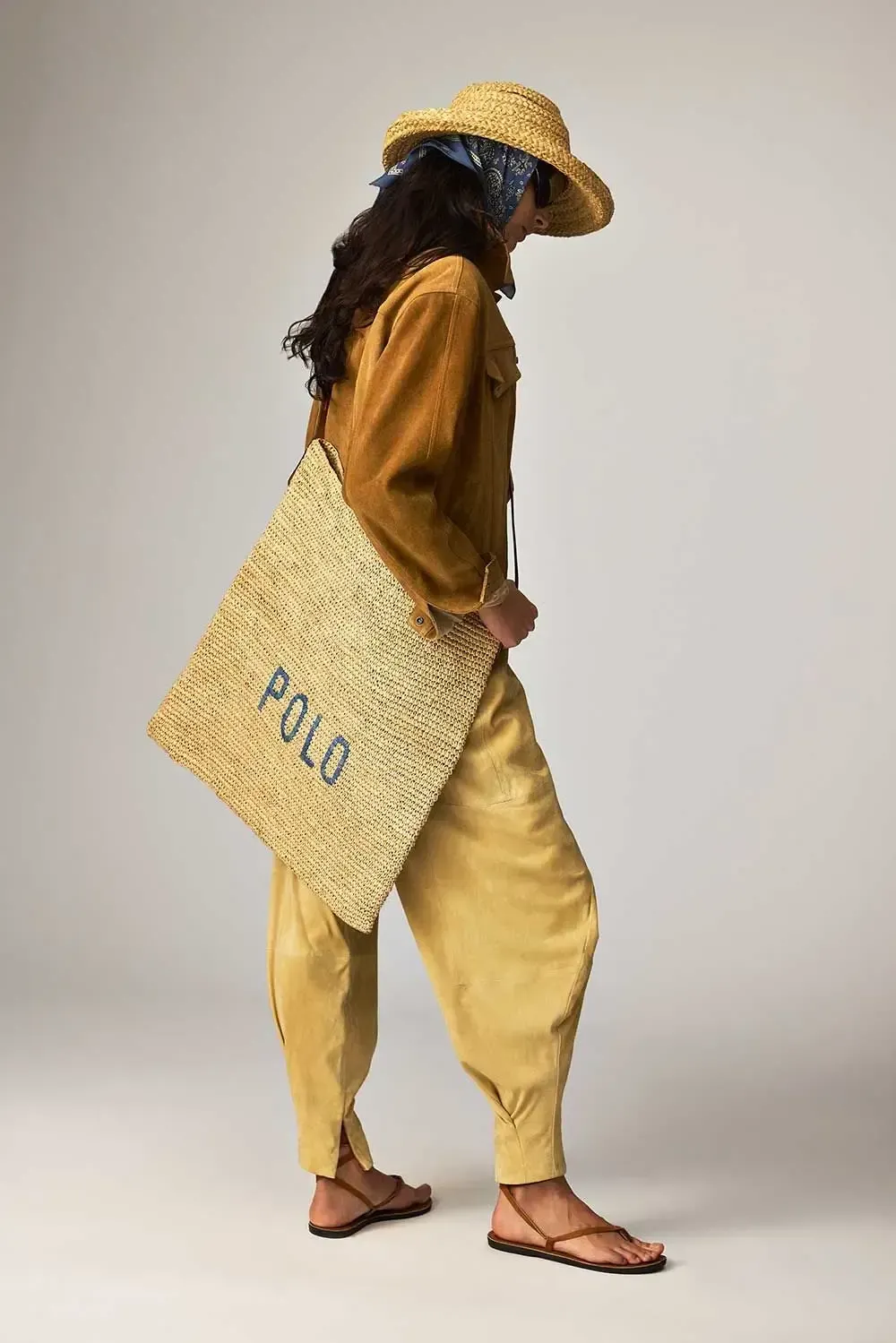 En kvinde iført stråhat og holder en stråtaske.