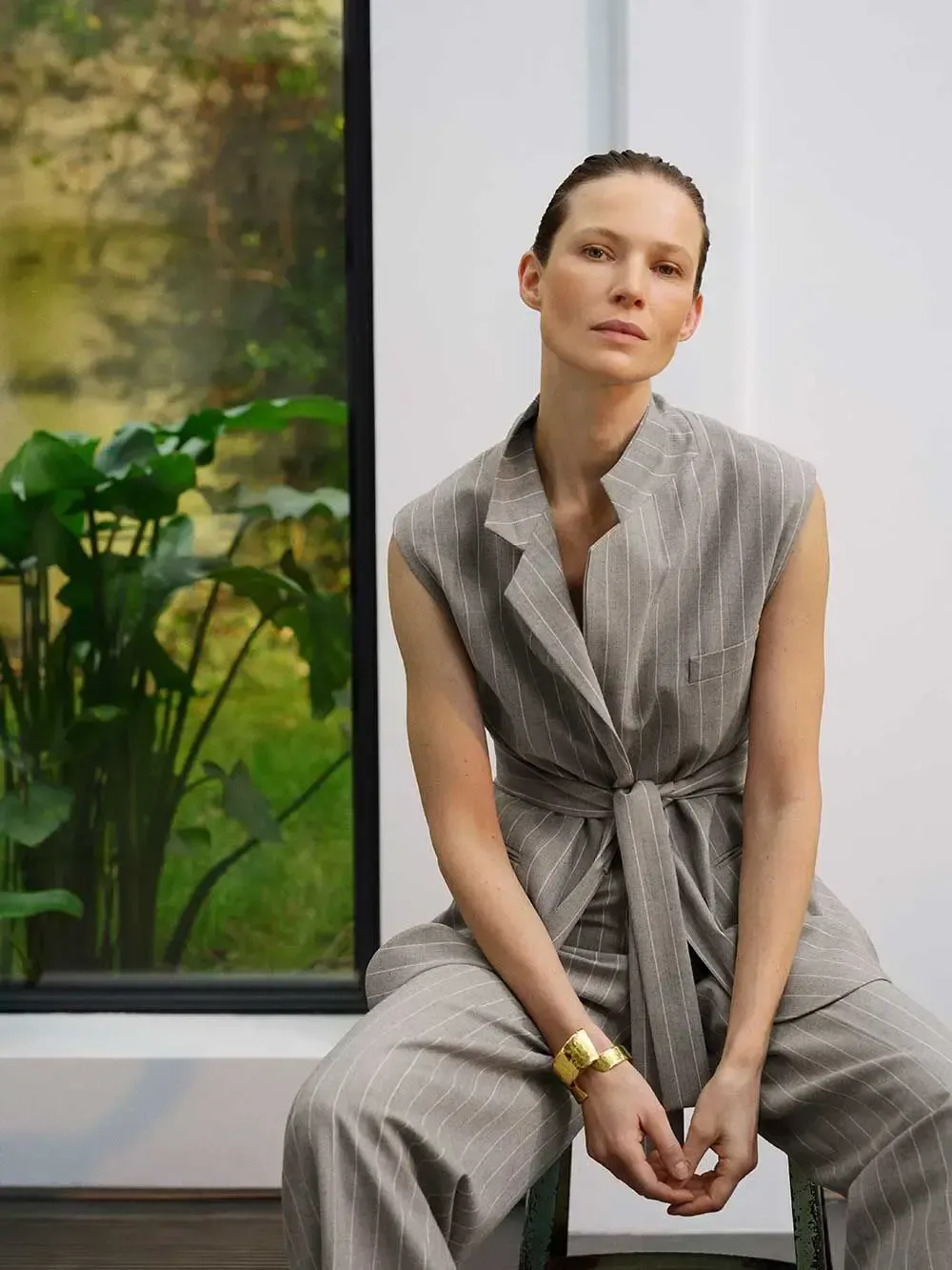 En kvinde sidder på en stol foran et vindue.