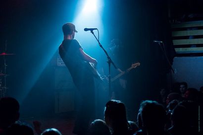 A man is playing a guitar on stage in front of a crowd.