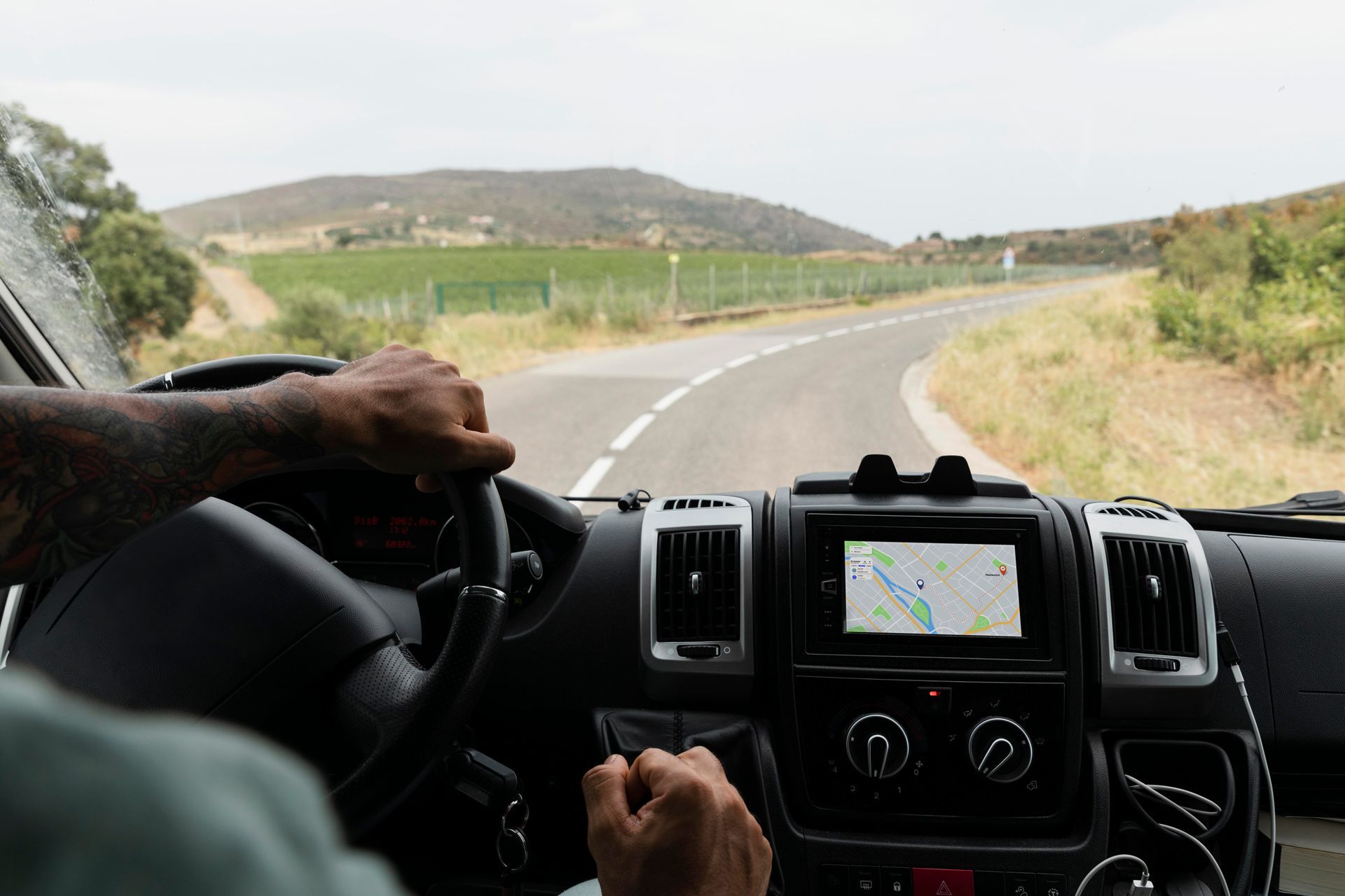 Um homem está dirigindo uma van em uma estrada rural.