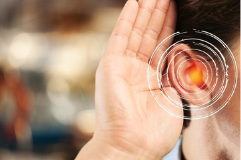 A woman holding her hand behind the ear, struggling with hearing.