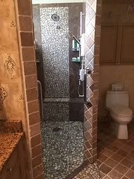 Bathroom with stone-tiled walk-in shower, toilet, and tan-colored walls.