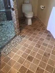 Bathroom with a toilet, shower, and square tile flooring.