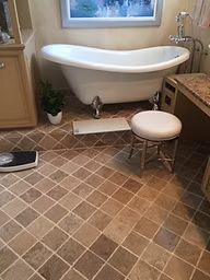 Bathroom with a claw-foot tub, vanity, stool, and tile floor.