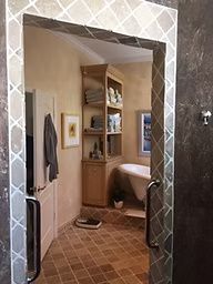Bathroom with a patterned tile doorway, showing a cabinet, towels, and a bathtub.