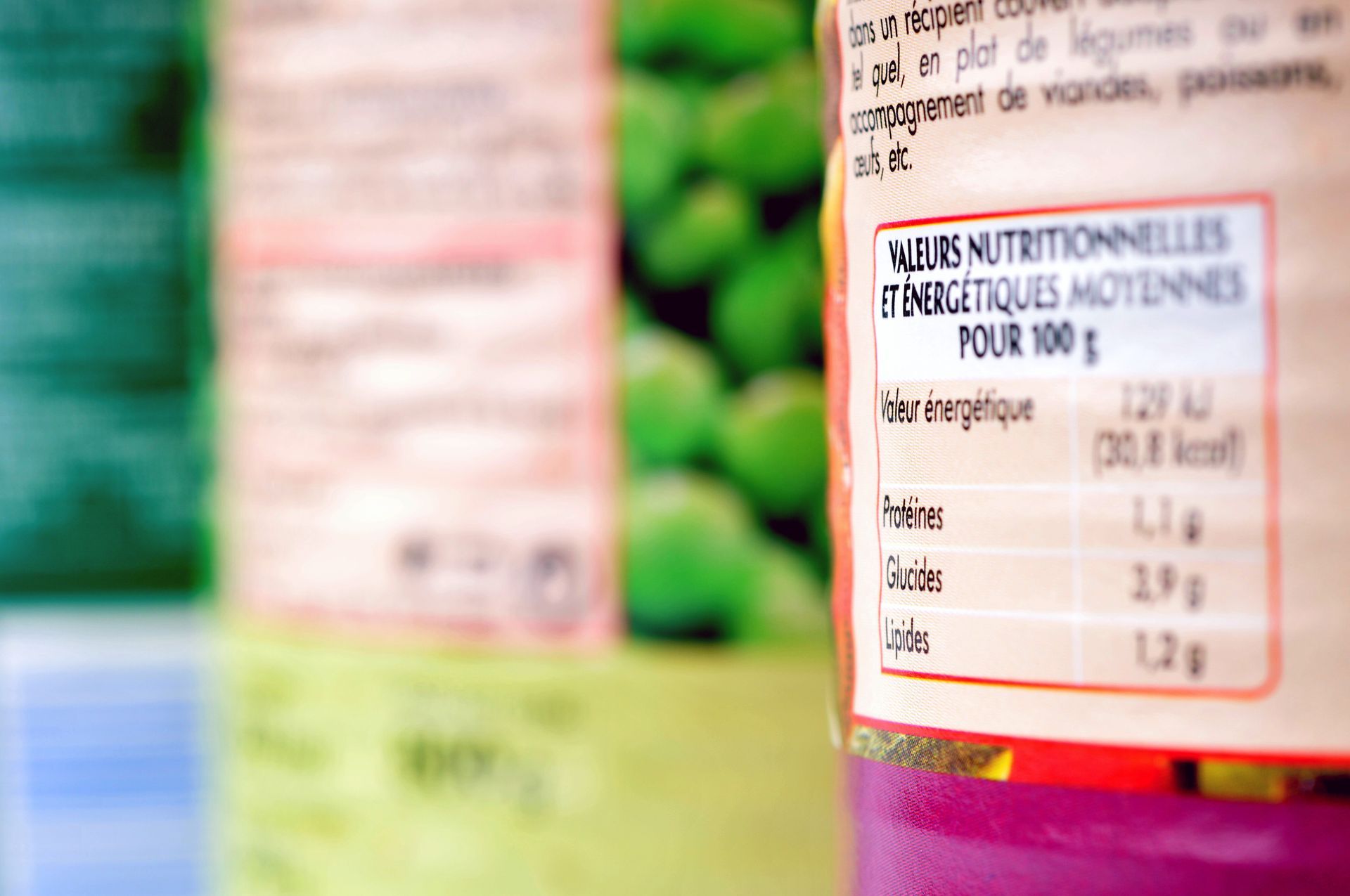 Gros plan sur l'étiquette d'un emballage alimentaire, mettant en évidence les valeurs nutritionnelles pour 100 grammes, avec des éléments flous en arrière-plan.