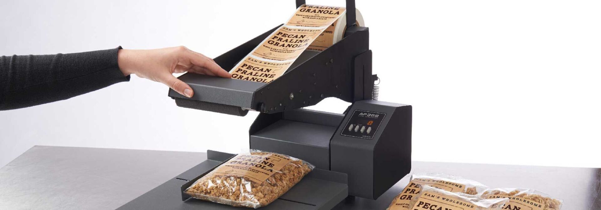 Une personne utilise une étiqueteuse de table pour apposer des étiquettes sur un produit alimentaire emballé.