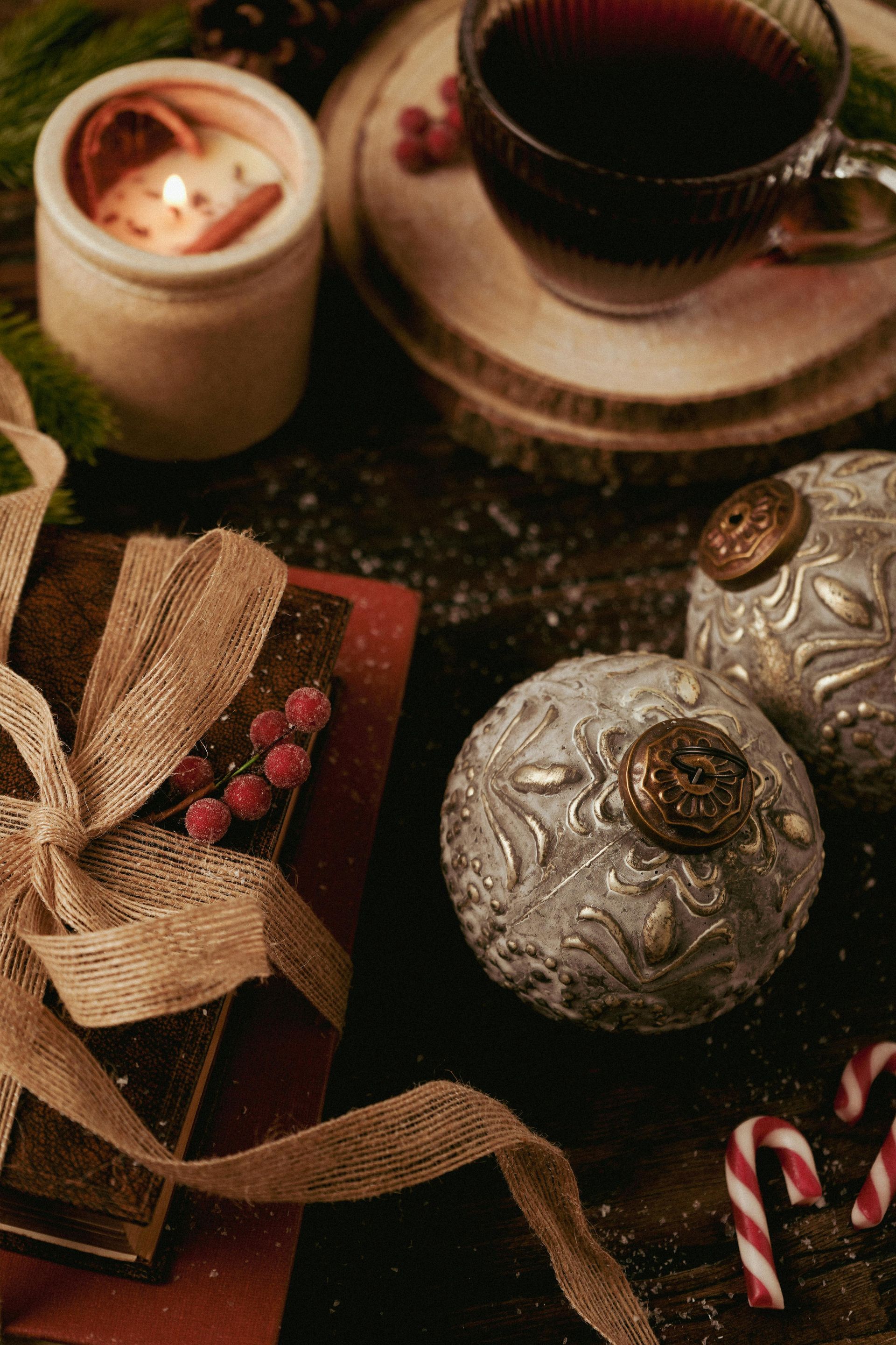 Christmas ornaments on a table with ribbon and holiday drinks.
