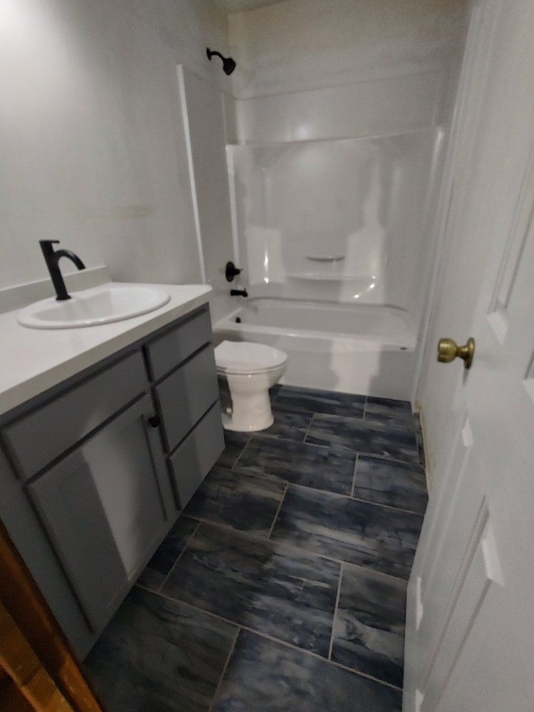Bathroom with a gray vanity, white sink, and blue tiled floor.