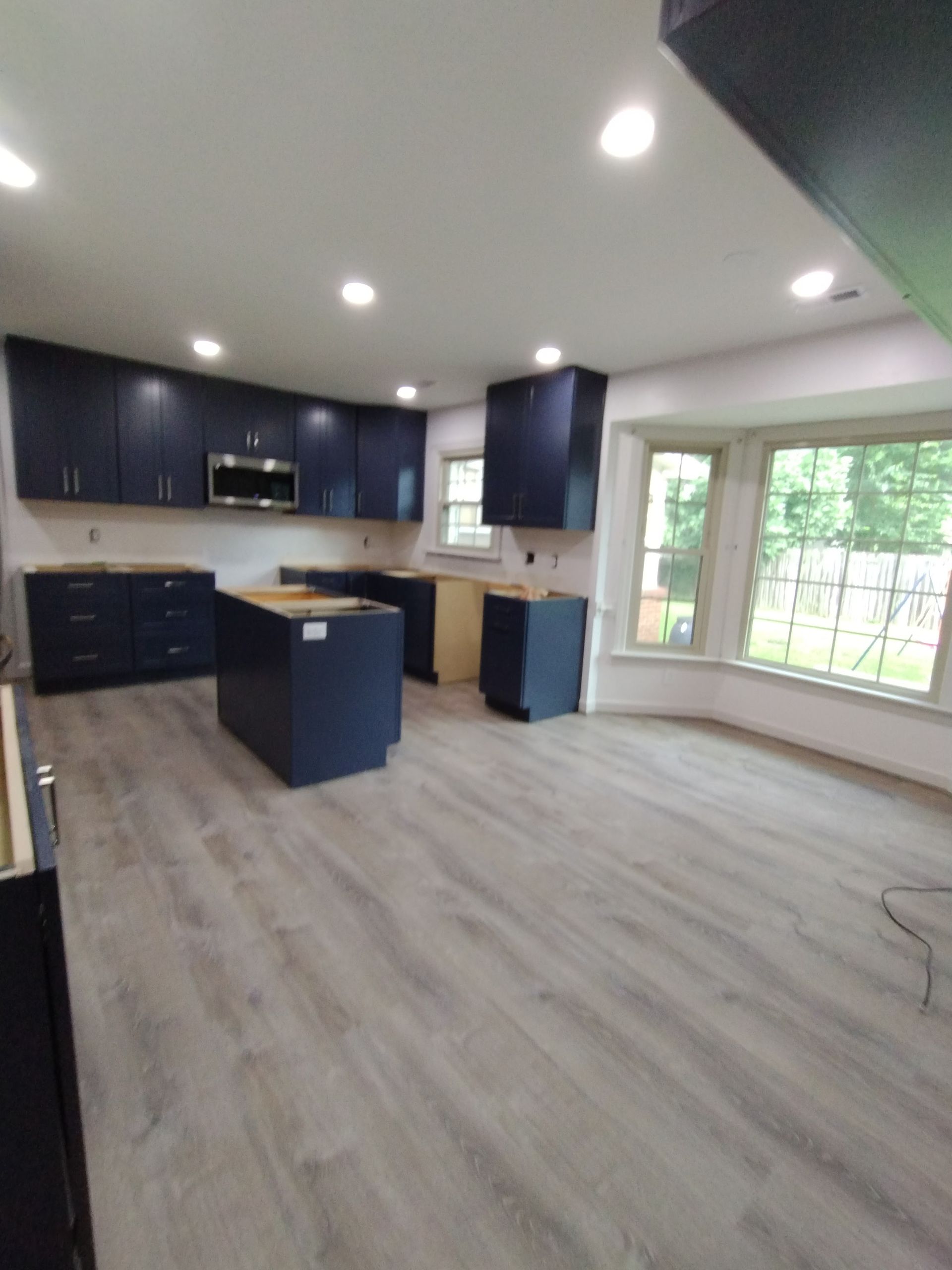 Navy blue kitchen cabinets under construction; light wood-look flooring.
