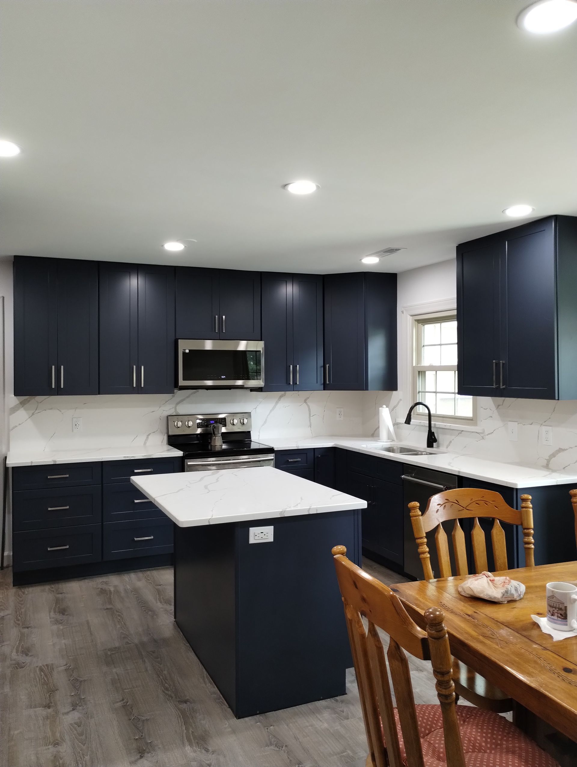 Navy blue kitchen cabinets with white countertops and island.