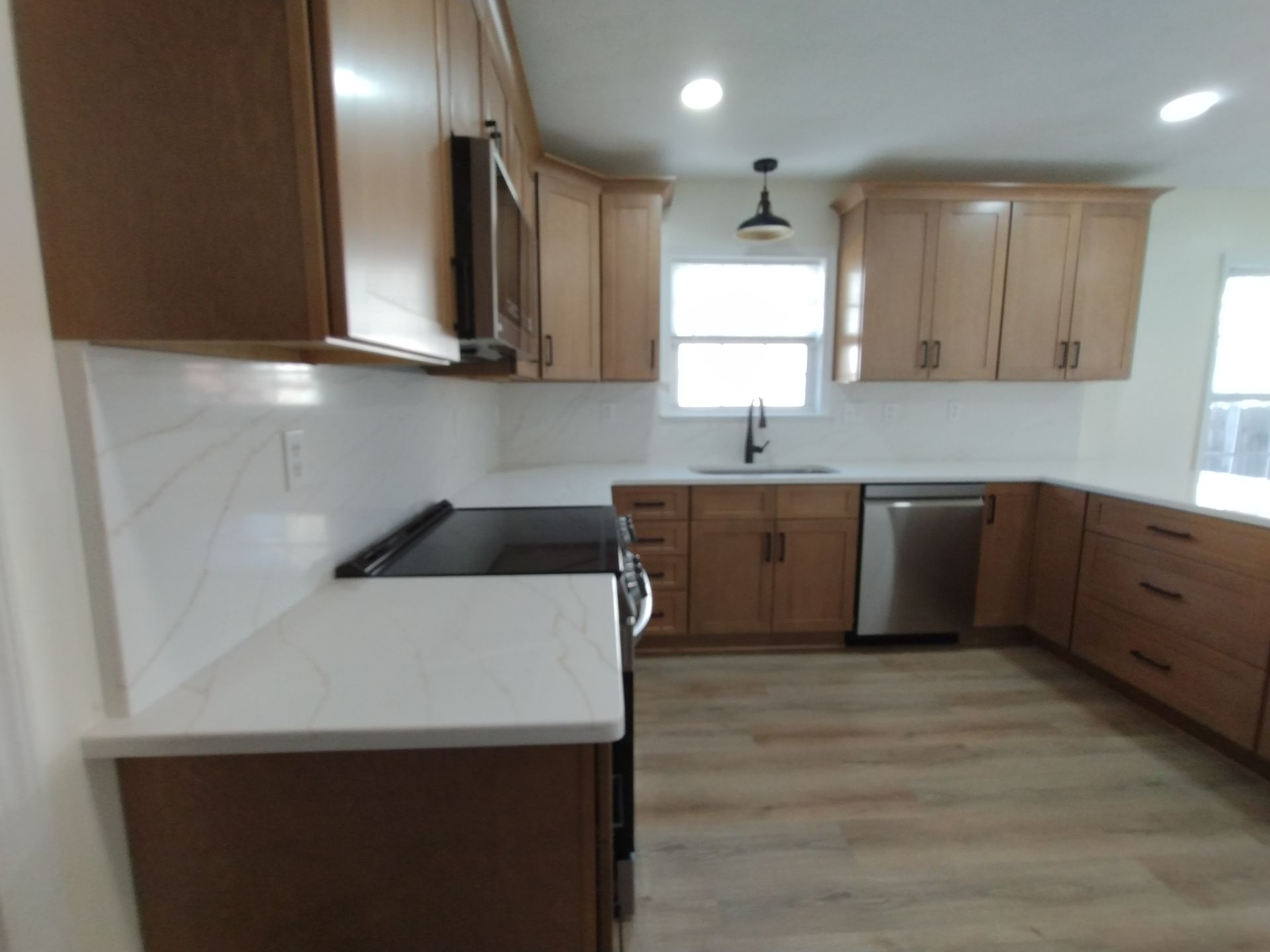 Modern kitchen with light wood cabinets, white countertops, and stainless steel appliances.