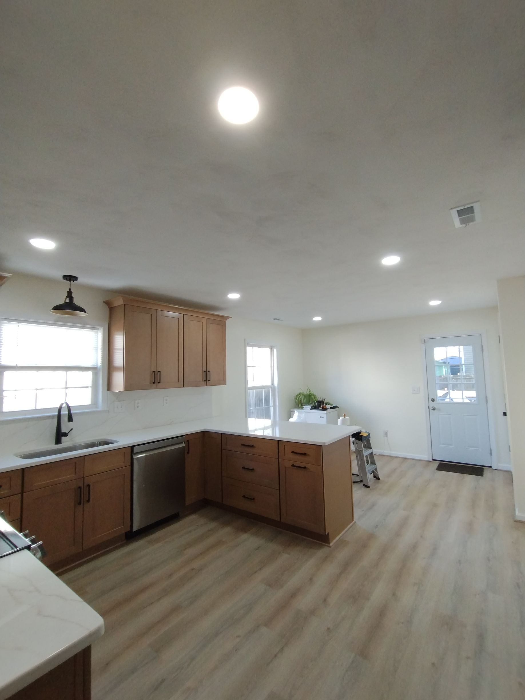 Modern kitchen with light wood cabinets, stainless steel appliances, and recessed lighting.