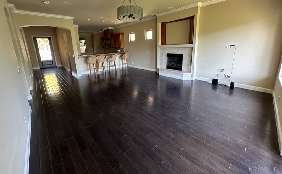 An empty living room with hardwood floors and a fireplace.