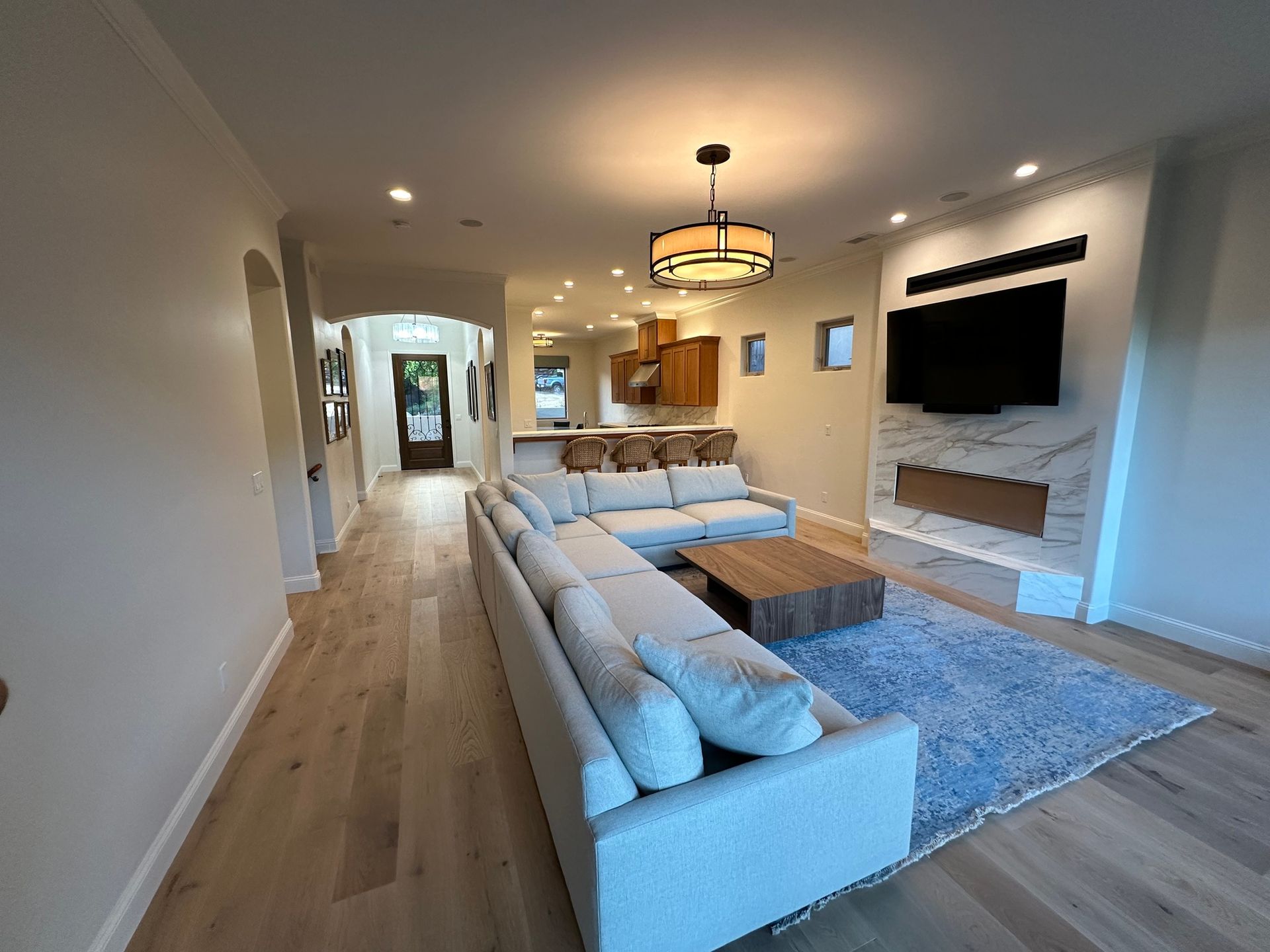 Spacious living room with light wood floors, a large sectional sofa, and a marble fireplace.