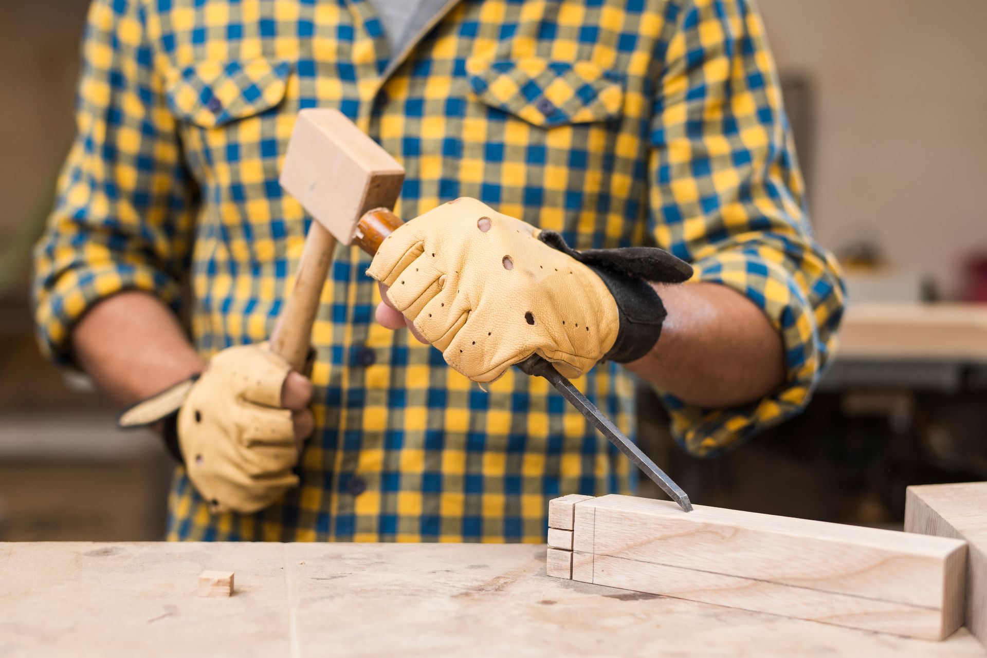 A man is hammering a nail into a piece of wood.