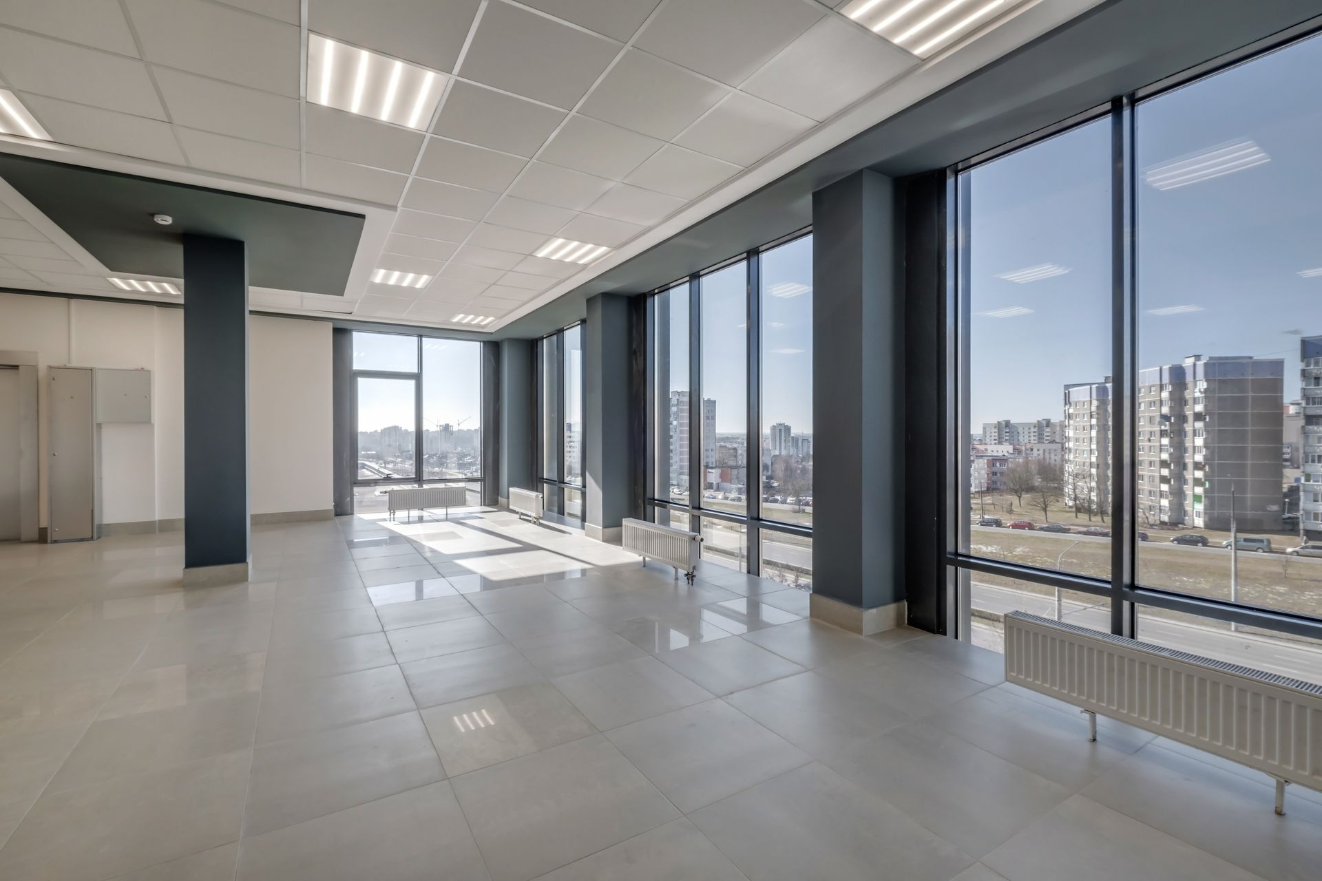 A large empty room with a lot of windows and a radiator.