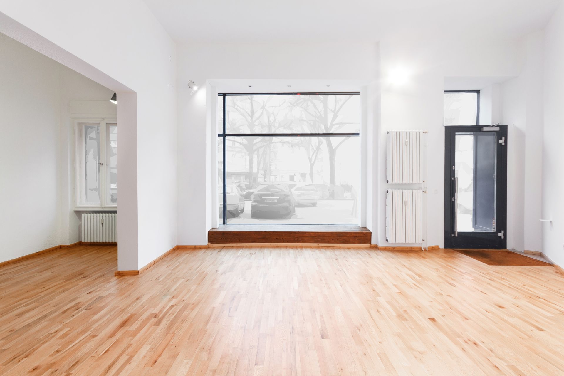 An empty room with hardwood floors and a large window.