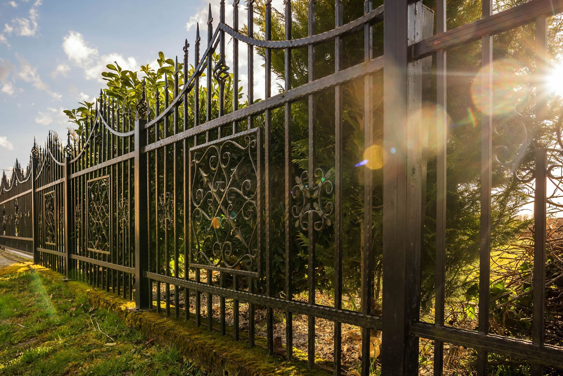A wrought iron fence surrounds a lush green field.