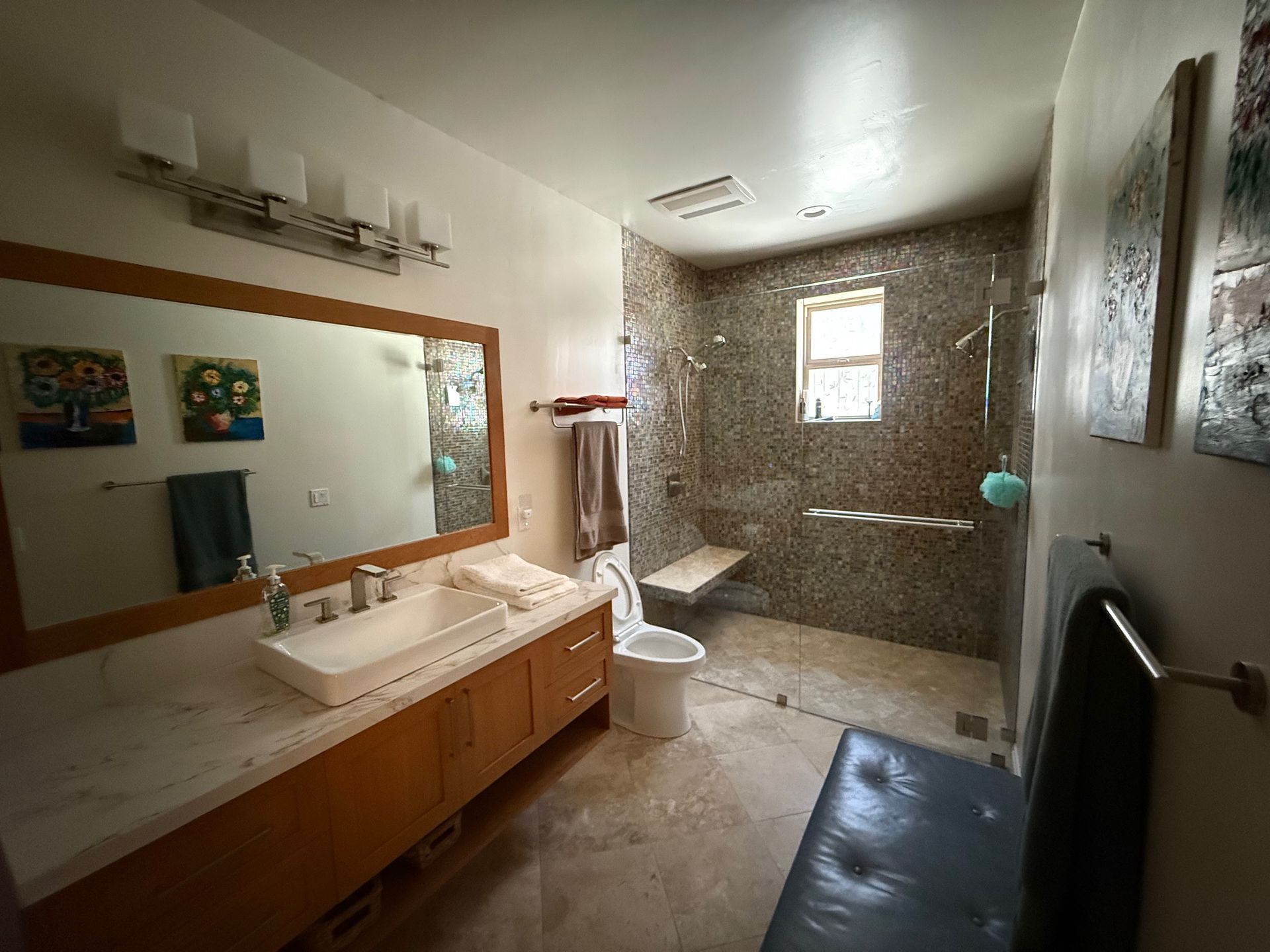 A bathroom with a sink , toilet , mirror and walk in shower.