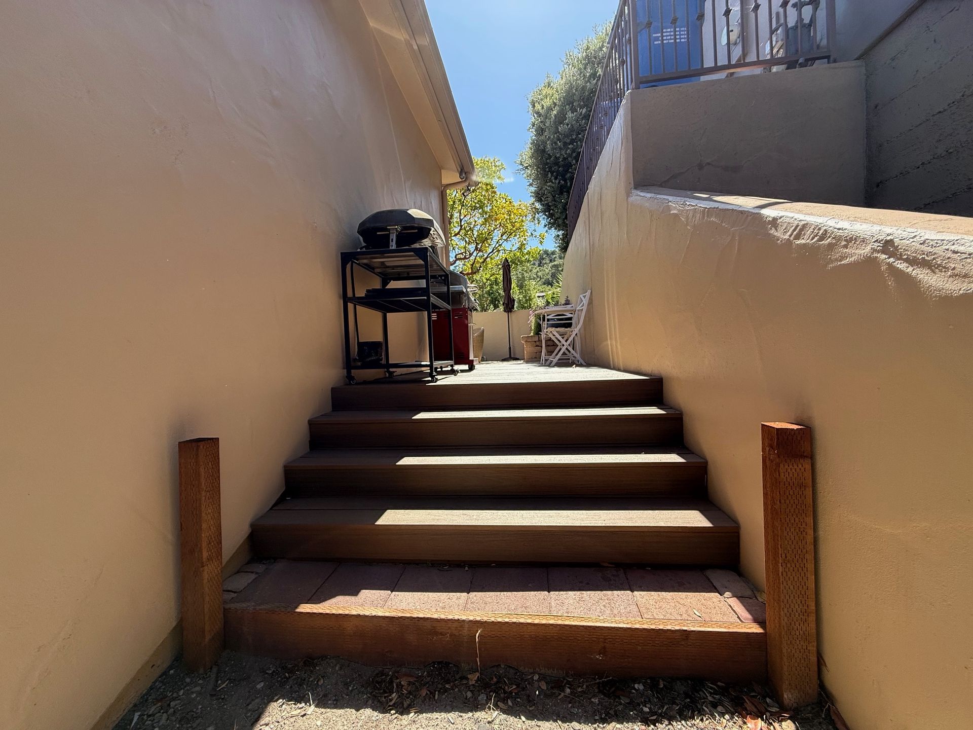 A set of stairs leading up to a patio with a grill in the background.