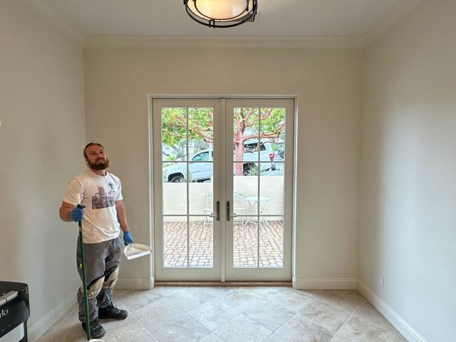 A man is standing in an empty room in front of a window.