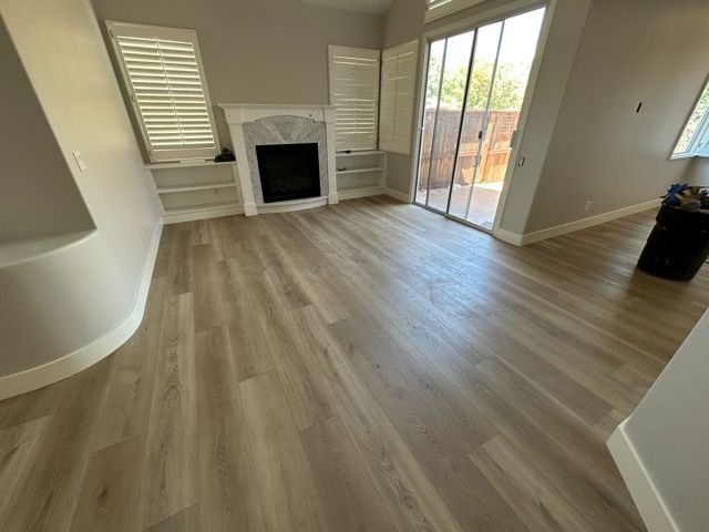 A living room with hardwood floors , a fireplace and sliding glass doors.