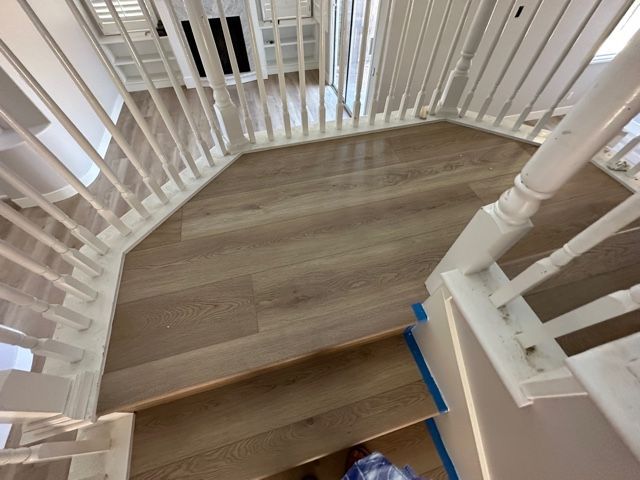A staircase with a white railing and a wooden floor