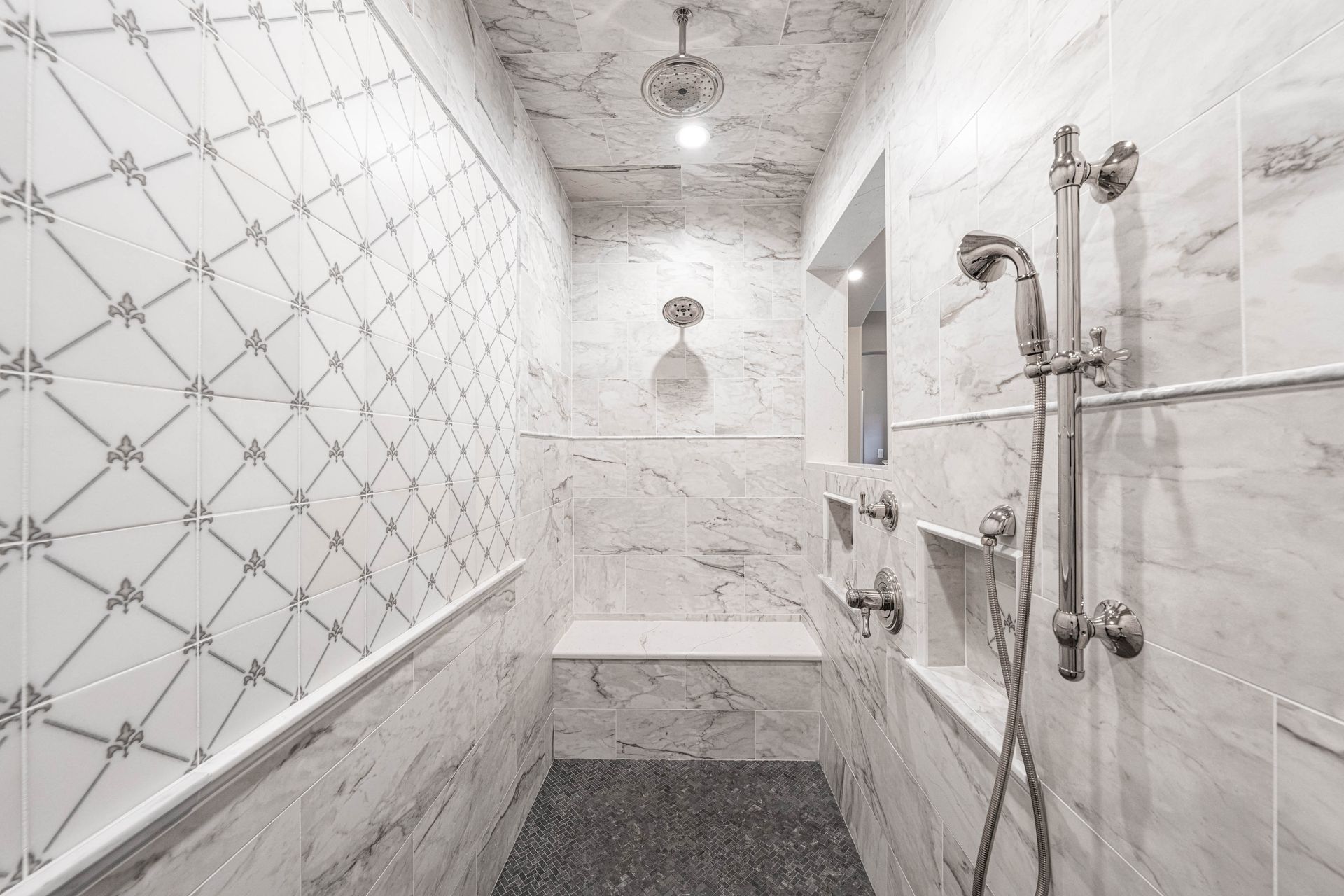 Elegant marble shower with patterned wall, bench, and multiple shower heads.