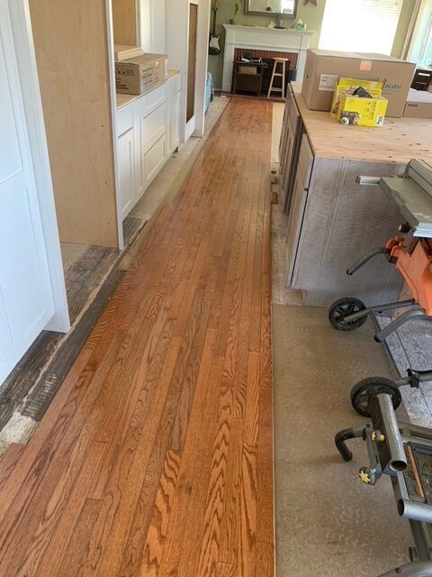 A long hallway with hardwood floors and a table saw.
