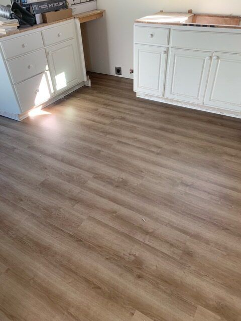 A kitchen with hardwood floors and white cabinets.