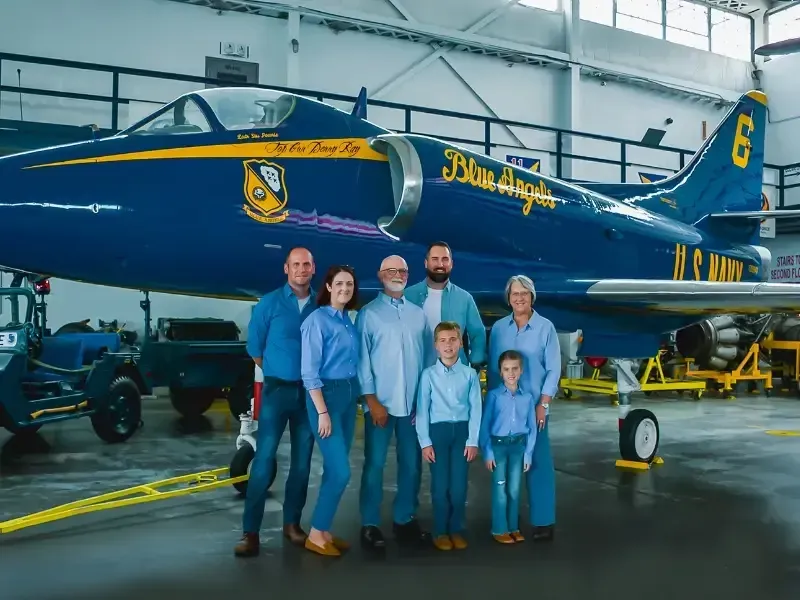 A group of people standing in front of a blue airplane.