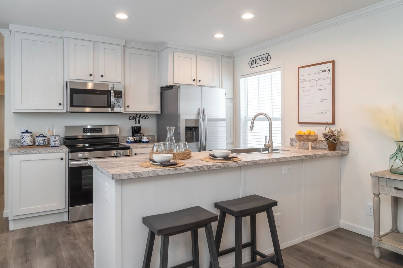 White kitchen with stainless steel appliances, breakfast bar, and two stools.