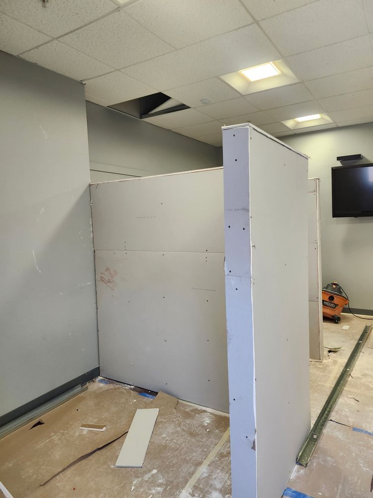 Drywall being installed for a room partition in an office setting.