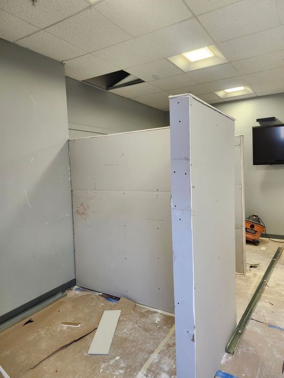 Drywall being installed for a room partition in an office setting.