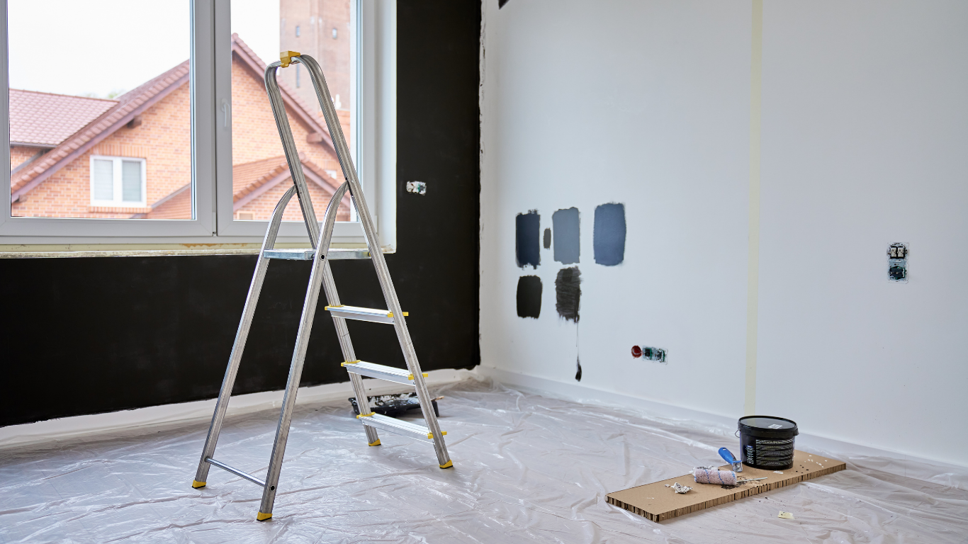 Room being painted, one black wall, ladder, paint swatches, and a window.