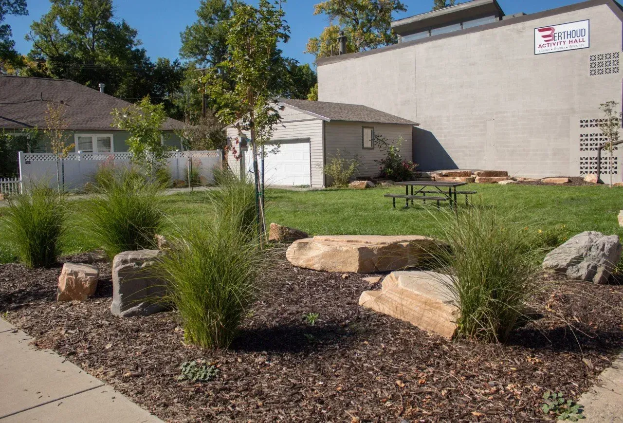 Lush landscaping with rocks, grasses, and mulch in front of a building.