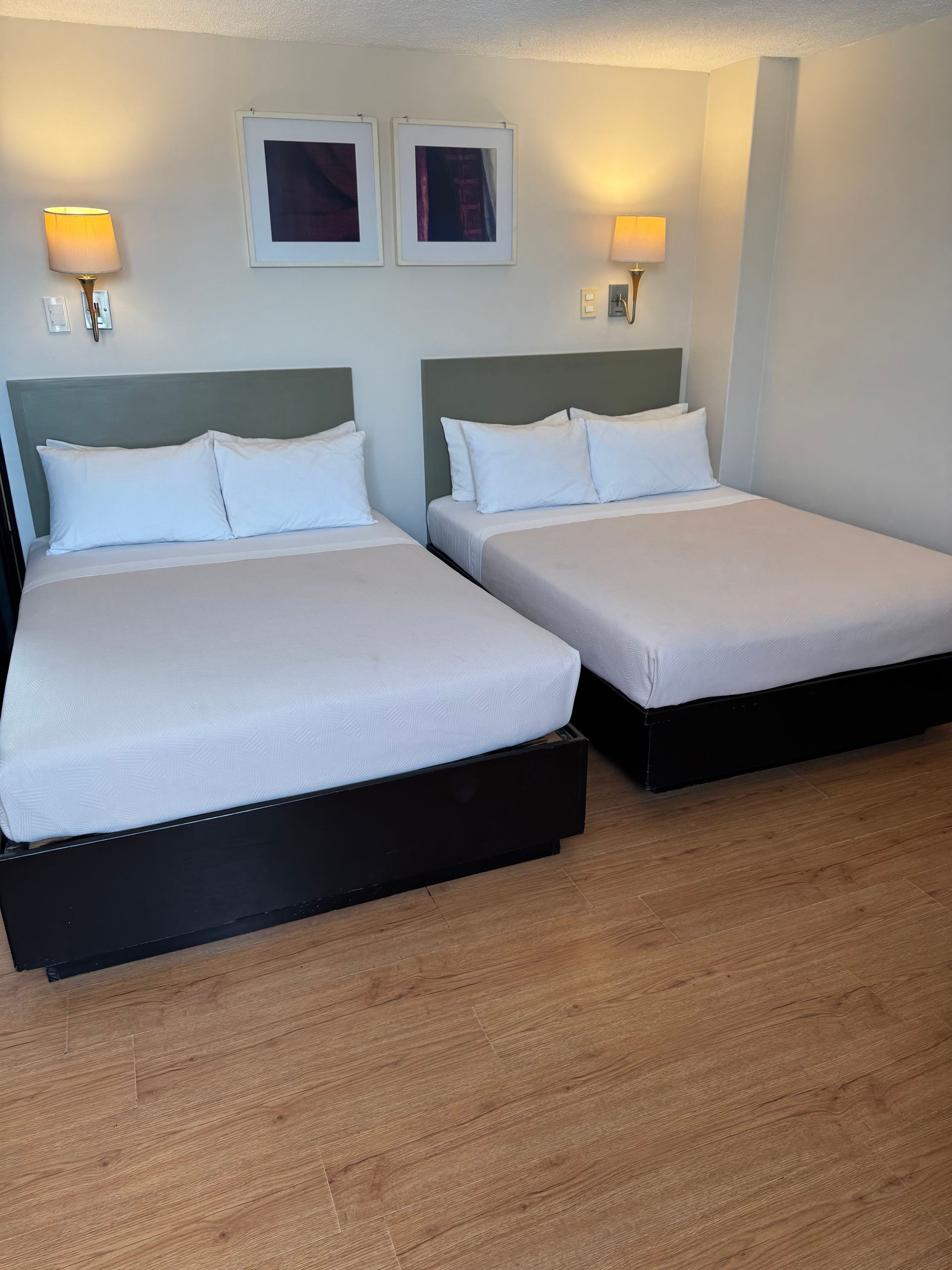 Bedroom with a bed, nightstand, and a patterned wallpaper accent wall, reflected in a framed mirror.