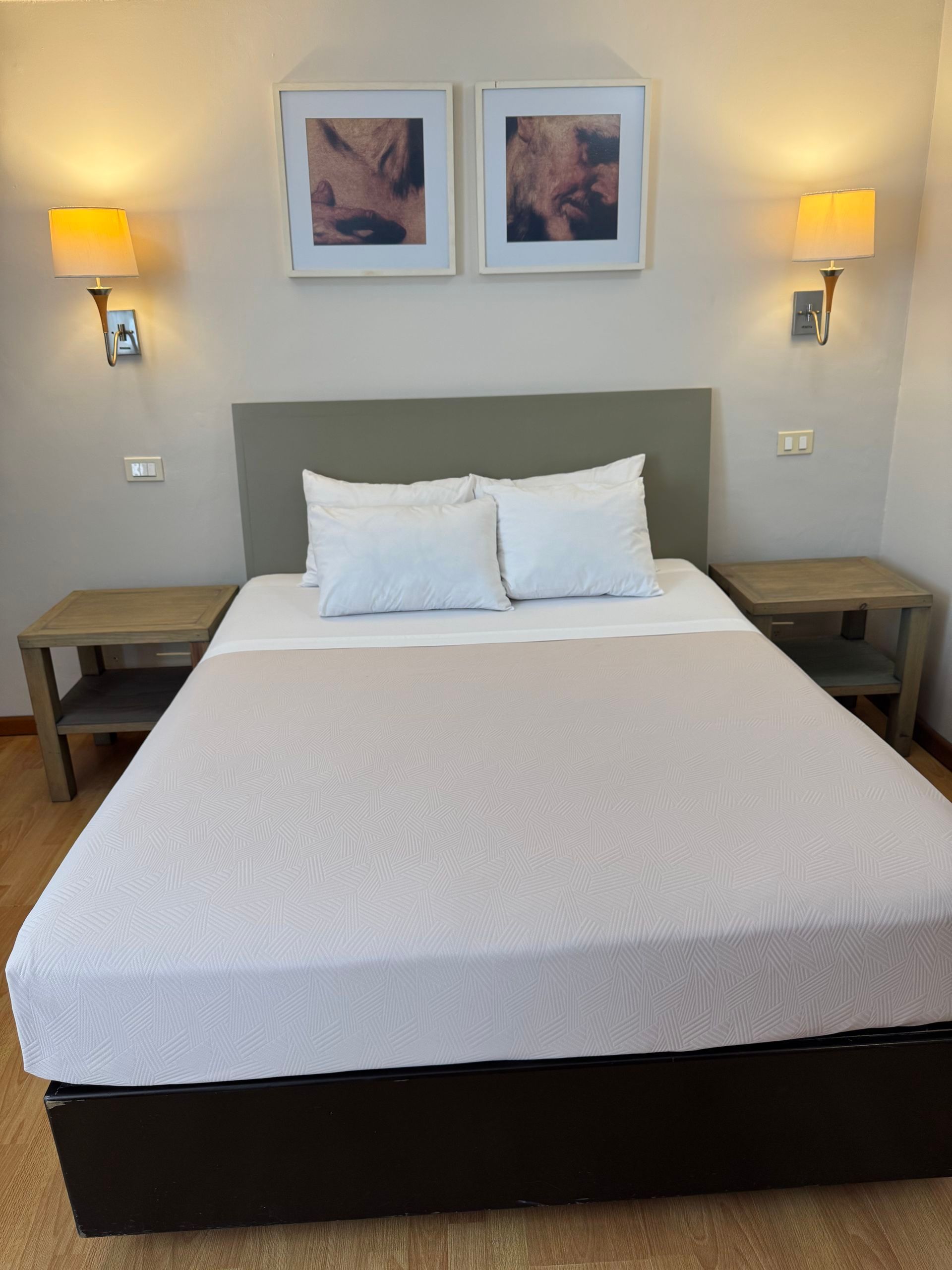 Bedroom with a bed, nightstand, and a patterned wallpaper accent wall, reflected in a framed mirror.